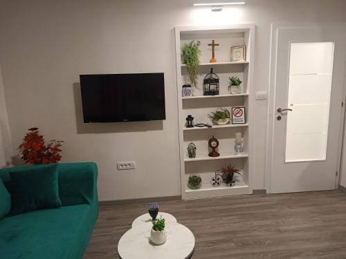 a living room with a green couch and a tv at Apartment GORA in Međugorje