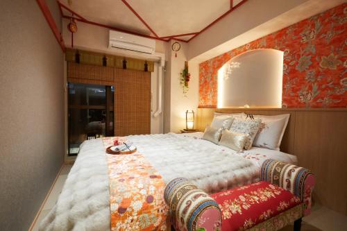 sypialnia z dużym łóżkiem z czerwoną ścianą w obiekcie Papillon Paradis Higashi-Shinjuku w Tokio