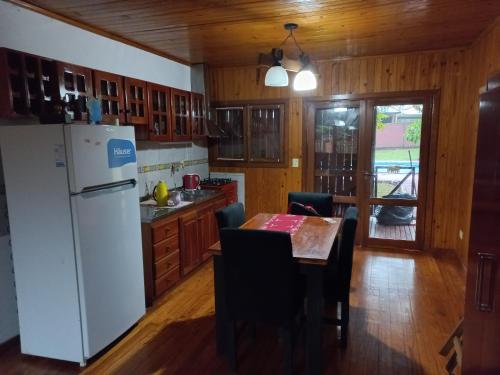 a kitchen with a table and a white refrigerator at Cabañas Raíces Pampeanas in Puerto Iguazú