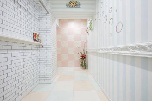 um corredor com uma parede de azulejos brancos e cor-de-rosa em Papillon Paradis Higashi-Shinjuku em Tóquio