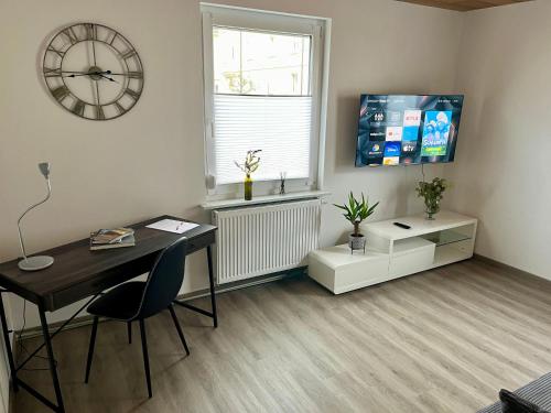 Habitación con escritorio y reloj en la pared en Ferienwohnung am Fuße Honberg, en Tuttlingen