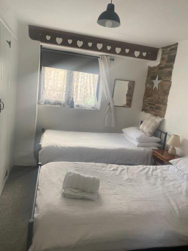 a bedroom with three beds and a window at Horseshoe Cottage in Looe