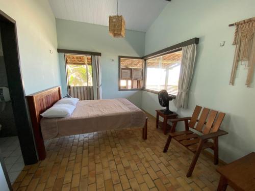 a bedroom with a bed and a chair and two windows at Tabatinga Beach Hotel in Nísia Floresta