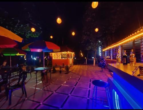 eine Bar mit Stühlen und Sonnenschirmen in der Nacht in der Unterkunft Basundhara Resort Cum Family Restaurant in Kharagpur