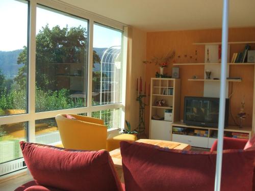 a living room with red chairs and a large window at Ferienwohnung Bergblick in Zella-Mehlis
