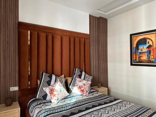 a bedroom with a bed with a wooden headboard and pillows at Appartement la gare Rabat ville in Rabat