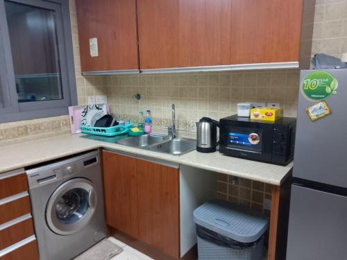 uma cozinha com um lavatório e uma máquina de lavar roupa em Top House Hostel em Abu Dhabi