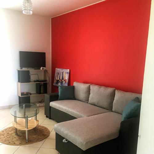 a living room with a couch and a red wall at l'HABITATION in Le Gosier