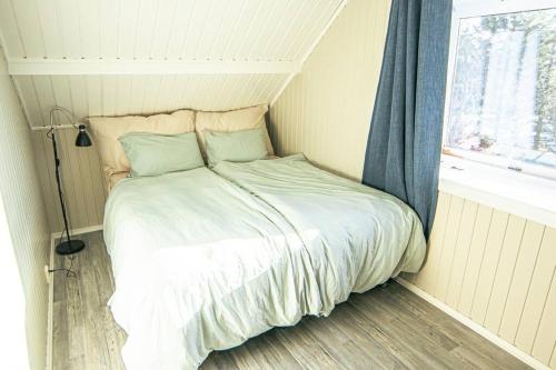 a bed in a small room with a window at Koselig toppleilighet med fantastisk utsikt in Svolvær