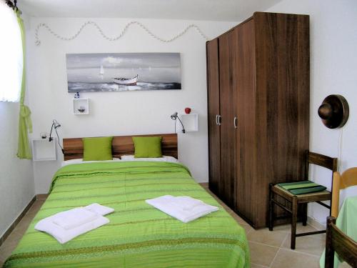 a bedroom with a green bed and a wooden cabinet at Studio Apartment Tamara in Krk