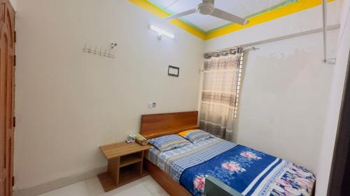 Dormitorio pequeño con cama y mesa en Hotel Jom Jom International, en Dhaka