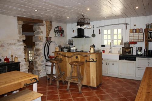 una cocina con armarios blancos y una barra con taburetes en LE DOMAINE DU SENS, en Frontenaud