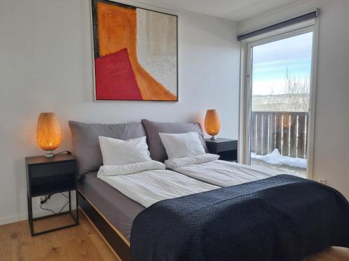 a bedroom with a bed with two lamps and a window at Lommedalen Panorama 55m2 in Bærums Verk