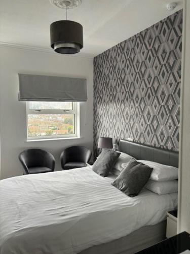 a bedroom with a bed with two chairs and a window at The Sandpiper Guest House in Torquay