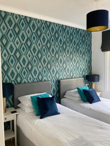 a bedroom with two beds with blue pillows on them at The Sandpiper Guest House in Torquay