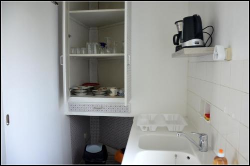 una cocina con fregadero y un armario con platos en studio "Au Bord de l'Eau" 2, en Chambon-sur-Voueize