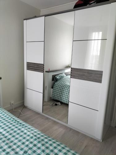 einen großen weißen Schrank mit einem Spiegel neben einem Bett in der Unterkunft Joy's apartment in Tours