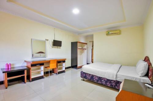 a hotel room with a bed and a desk at Malibou Hotel Medan in Tebingtinggi