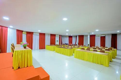 una sala de conferencias con mesas y sillas amarillas y cortinas rojas en Malibou Hotel en Tebingtinggi