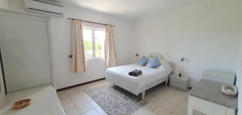 a white bedroom with a bed and a window at Beachfront Pereybere - Azur Beach Complex in Pereybere