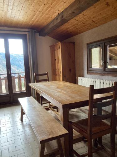 - une table et des chaises en bois dans une chambre avec fenêtre dans l'établissement le grand nant, à La Giettaz
