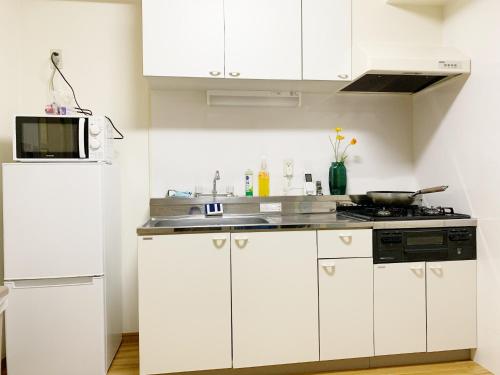 a white kitchen with a sink and a microwave at 精品新装修60平米2卧室阳光公寓#干湿分离#高速无限制网路#专用电梯直达#3站直达新宿#最大7人#itk501 in Tokyo