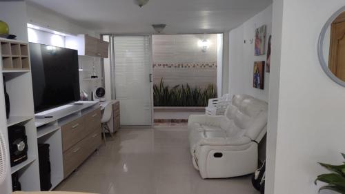 a white living room with a chair and a television at casa para festival vallenato in Valledupar