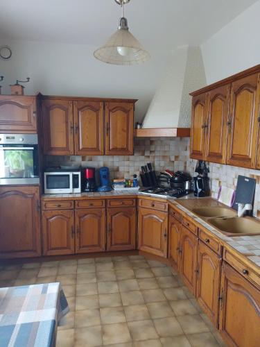 uma cozinha com armários de madeira e um micro-ondas em Location chez l habitant em Argentré-du-Plessis