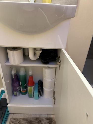 a bathroom cabinet with a sink and some toiletries at L-Houses in Dagenham