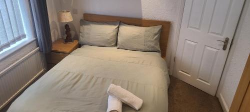 um pequeno quarto com uma cama com lençóis brancos e almofadas em Grand Near Etihad Stadium em Manchester