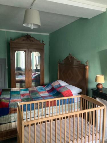 ein Kinderbett in einem Schlafzimmer mit grünen Wänden in der Unterkunft Chez Marie et Lucien in Vianges