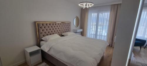 - une chambre avec un lit blanc et une grande tête de lit dans l'établissement RIVER WALK 908 ILIDZA Apartment Sarajevo, à Sarajevo