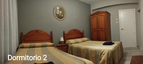 sypialnia z 2 łóżkami pojedynczymi i szafką w obiekcie Los Álamos w Meridzie