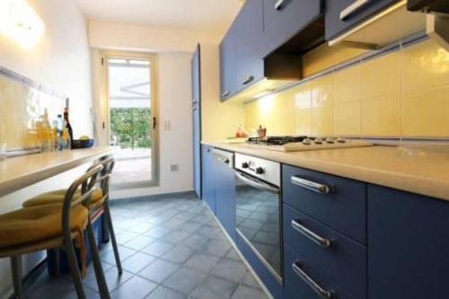 une cuisine avec des armoires bleues et une table et des chaises dans l'établissement FRONT DE MER Juan les Pins Cannes, à Antibes