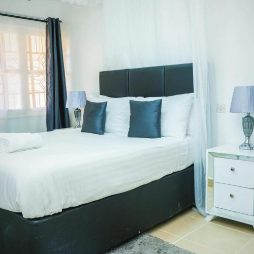a bedroom with a large bed with blue pillows at Sofitel Executive 4 bedrooms Milimani in Kisumu