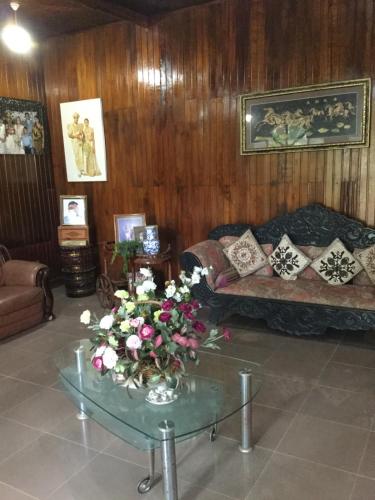 ein Wohnzimmer mit einem Sofa und einem Tisch mit Blumen in der Unterkunft Maliga Inn in Gampola