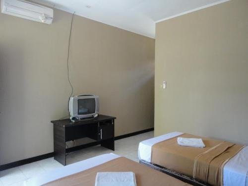 Cette chambre comprend 2 lits et une télévision sur une table. dans l'établissement Pakuna Beach, à Senggigi