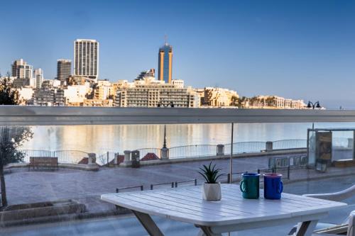 a table on a balcony with a view of a city at Stunning - SunnySide 3-Bedroom in Sliema