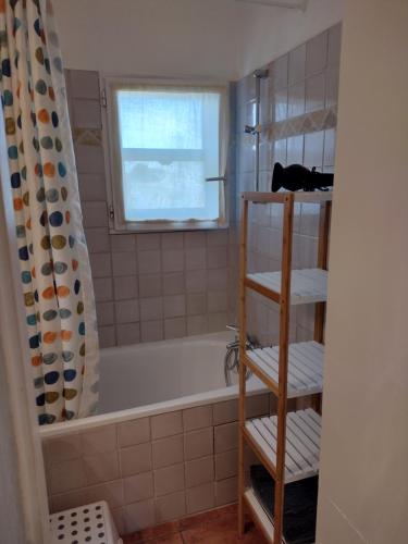 een badkamer met een bad en een raam bij Vacances en Camargue proche de la mer climatisé in Aigues-Mortes