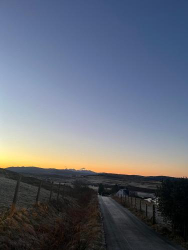 an empty road with the sunset in the background at Sgothan Dearg in Portree