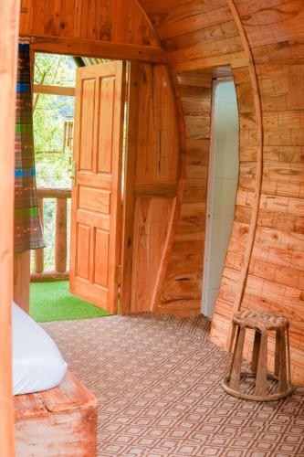 a wooden cabin with a wooden door and a stool at A Hòa Homestay in Ye Yen Sun Cay