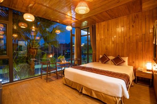 a bedroom with a bed and a large window at Tam Coc Serenity Hotel & Bungalow in Ninh Binh