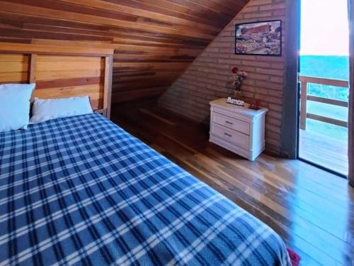 1 dormitorio con 1 cama y pared de madera en Chácara Bela Vista en Taquara