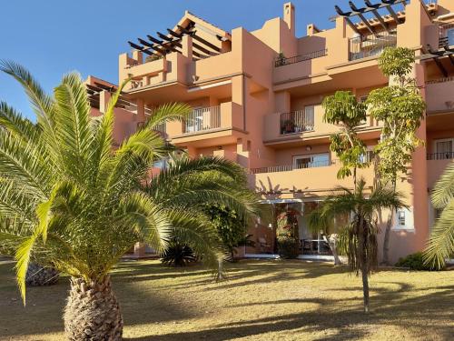 a building with palm trees in front of it at Alegría - Mar Menor Golf Resort in Torre-Pacheco
