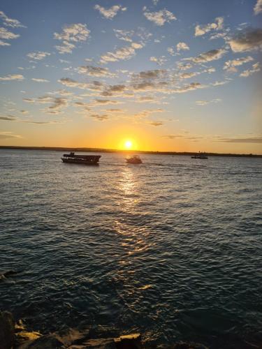 a sunset on the water with boats in the water at Apto novo! Recém entregue in Cabedelo