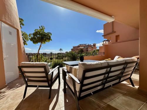 a patio with two chairs and a table on a balcony at Alegría - Mar Menor Golf Resort in Torre-Pacheco