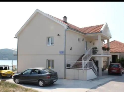 a white house with a car parked in front of it at Apartment Potpara in Tivat