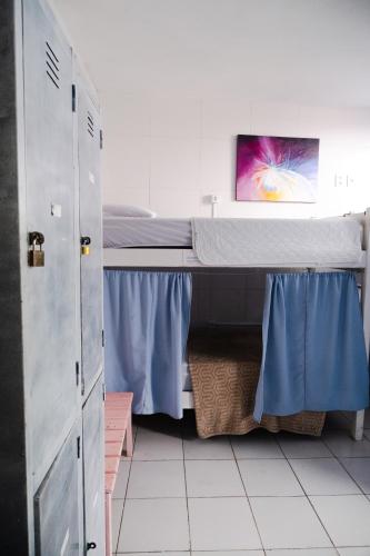 a bedroom with a bunk bed with blue curtains at Nomads Hostel Multicultural & Coworking in Salvador