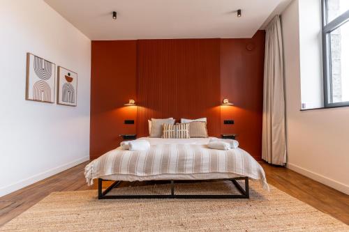 マルシュ・アン・ファメンヌにあるHôtel Le Manoirのベッドルーム1室(オレンジ色の壁の大型ベッド1台付)