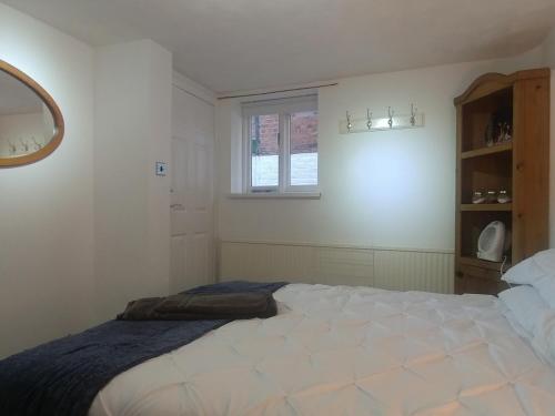 a white bedroom with a bed and a window at Ty Newydd Gwyn - G/F Room in Denbigh